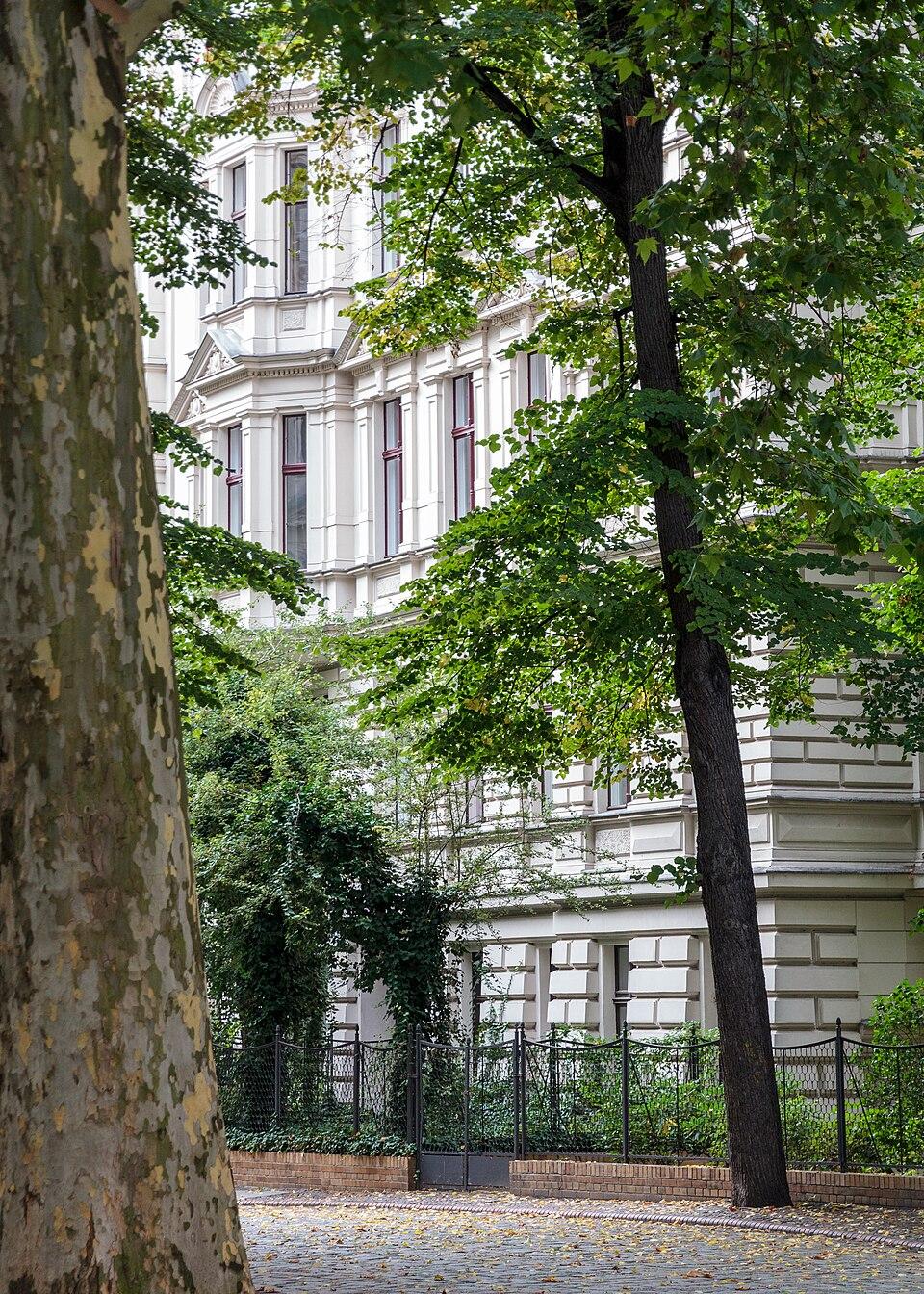 Ruhiger Wohnhof mit weißen Stuckfassaden, Bäumen und gepflastertem Weg in Riehmers Hofgarten, Berlin-Kreuzberg