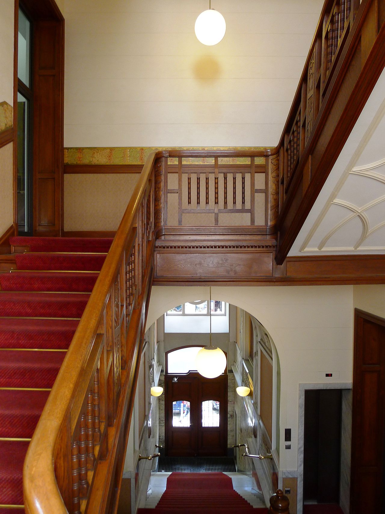 Historisches Treppenhaus mit geschwungenem Holzgeländer, rotem Läufer und Kugelleuchten, Meinekestraße, Berlin-Charlottenburg