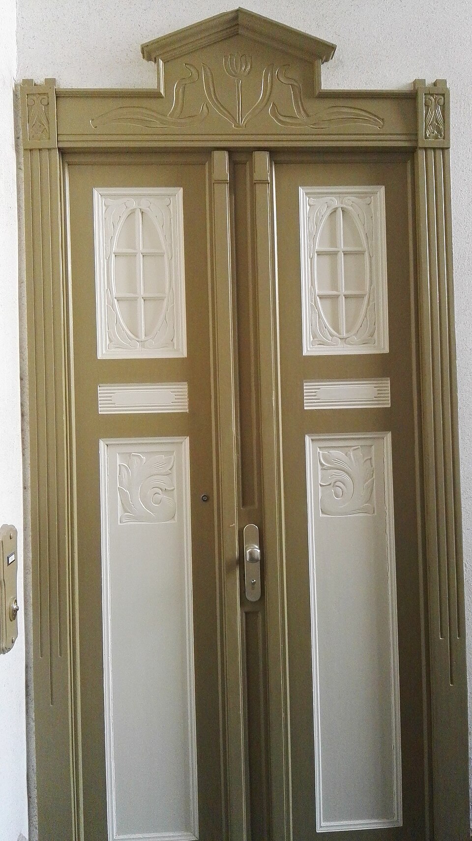 Zweiflügelige Jugendstil-Wohnungstür mit geschnitzten Ornamenten und ovalen Fenstern in einem Berliner Altbau